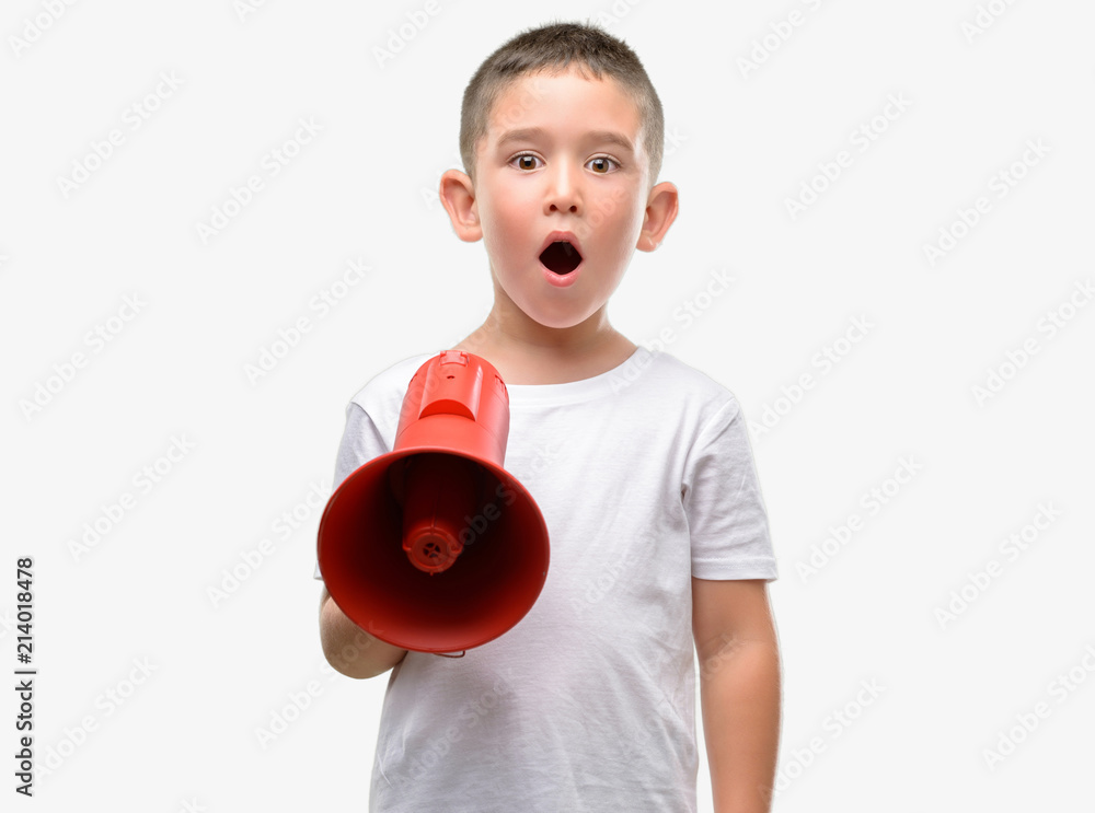 Dark haired little child holding megaphone scared in shock with a surprise face, afraid and excited with fear expression Dark haired little child holding megaphone scared in shock with a surprise face, afraid and excited with fear expression