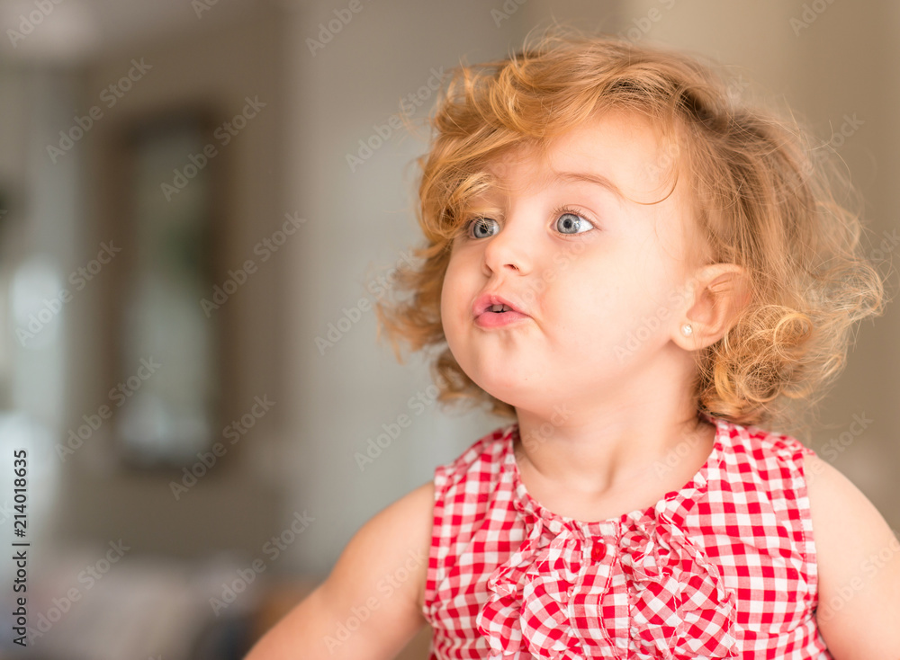 Beautiful blonde child with blue eyes eating candy at home. Beautiful blonde child with blue eyes eating candy at home.