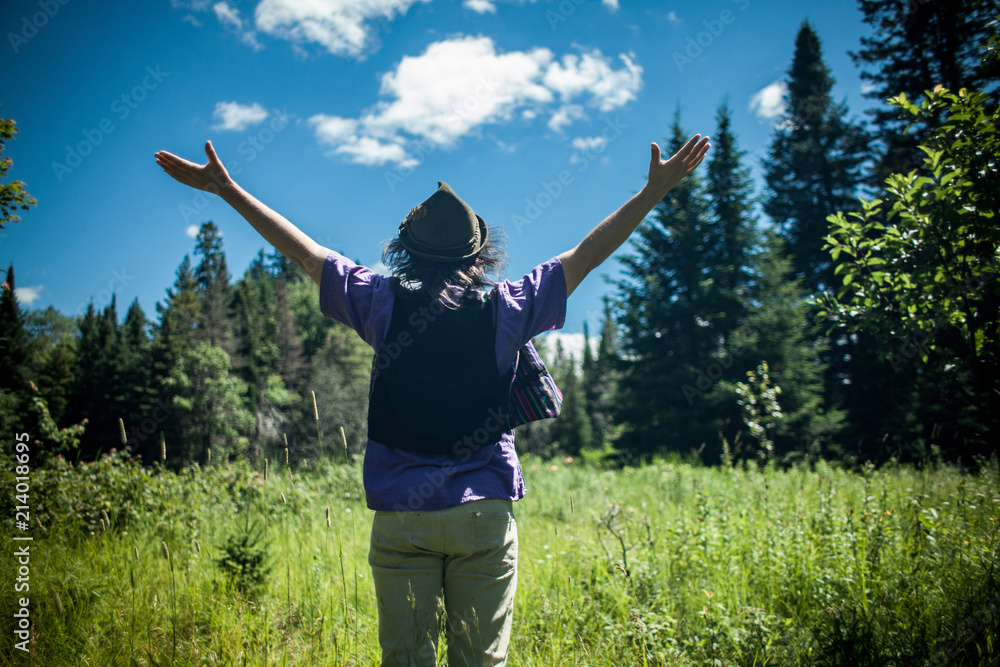 Man wearing hat with his arms up enjoying a beautiful sunny day in the nature, seen from behind Man wearing hat with his arms up enjoying a beautiful sunny day in the nature, seen from behind