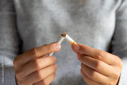 World No Tobacco Day, May 31. STOP Smoking. Close up woman hand breaking, crushing or destroying cigarettes on black background.