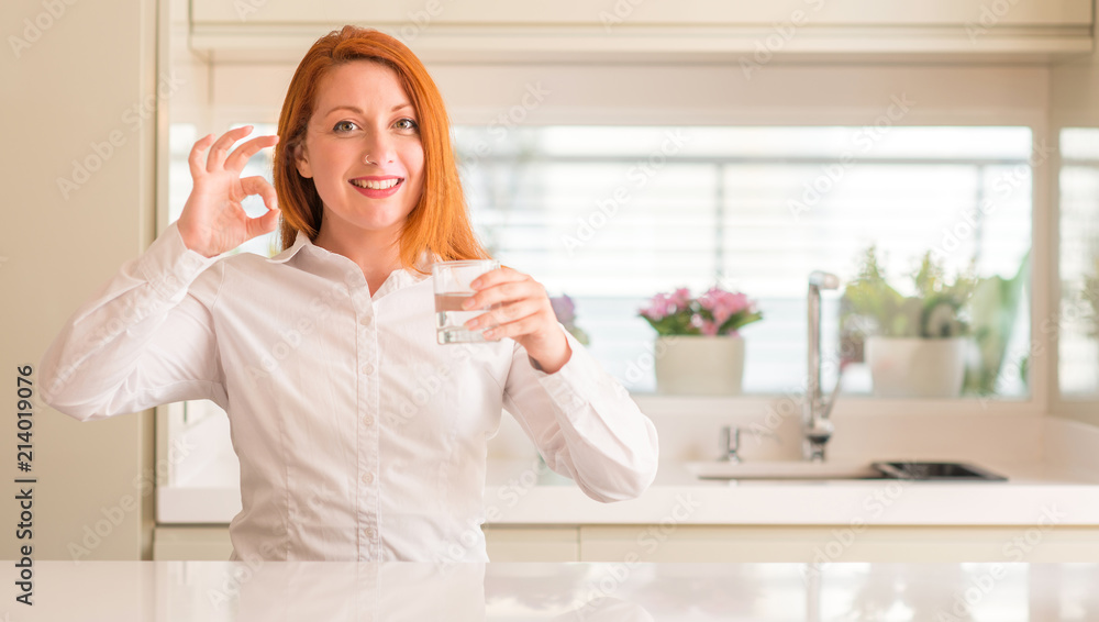 Thirsty redhead woman and glass of water doing ok sign with fingers, excellent symbol Thirsty redhead woman and glass of water doing ok sign with fingers, excellent symbol