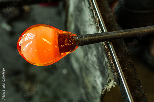 Vászonkép Glass-blower man working with hot ocher glass to make a blown glass lantern