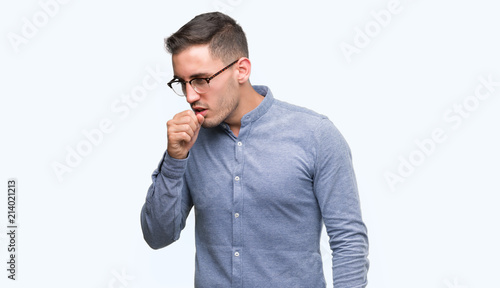 Handsome young elegant man wearing glasses feeling unwell and coughing as symptom for cold or bronchitis. Healthcare concept.