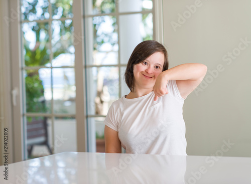 Down syndrome woman at home with surprise face pointing finger to himself