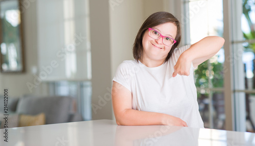 Down syndrome woman at home with surprise face pointing finger to himself