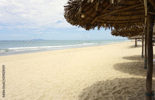 Sunny sandy beach with thatched shelters in Southeast Asia