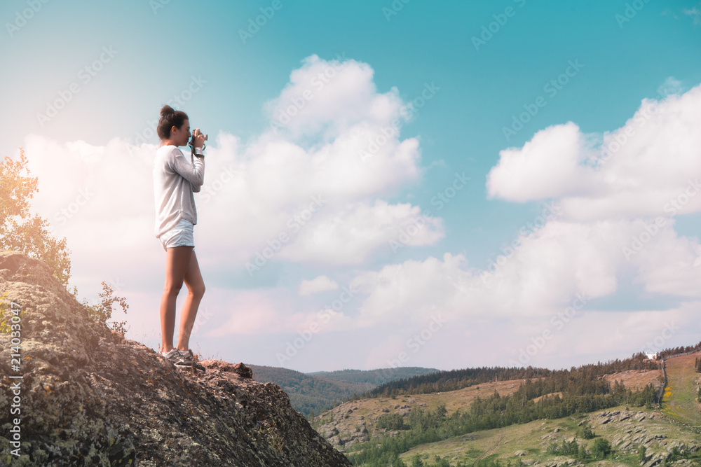 woman photographer takes a picture of a mountain landscape on the camera