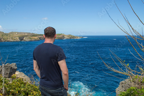 Lonely digital nomad traveler stands at the precipace alone on the rocky cliffs wondering about his thoughts. © Travis
