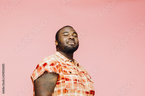 Portrait of a cool plus size man in orange shirt on pink background