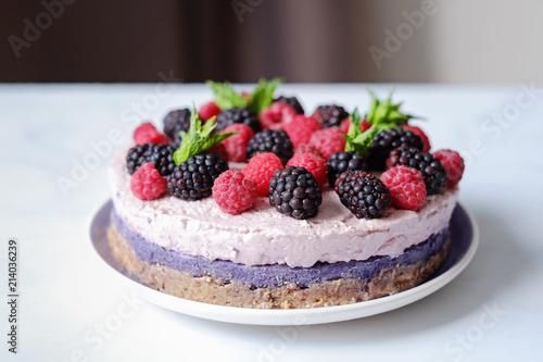 Raw vegan cake with raspberries and bluberries on white table