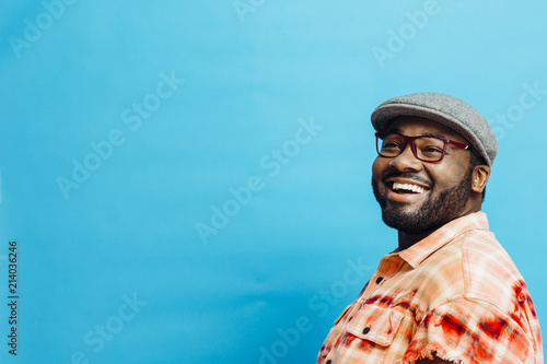 Fotografia Portrait of a happy man in orange shirt looking up, with blue copy space around