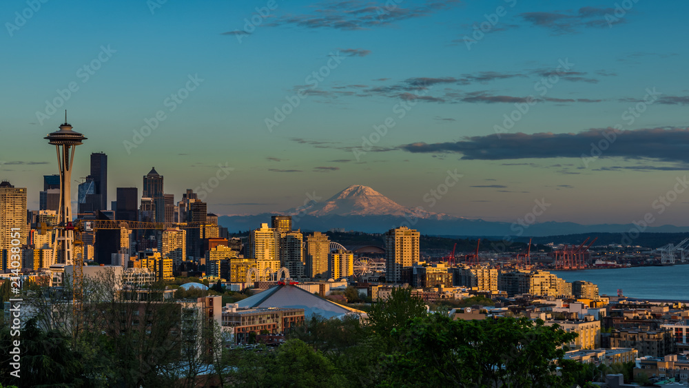 Seattle skyline lit by the setting sun with Mount Rainier