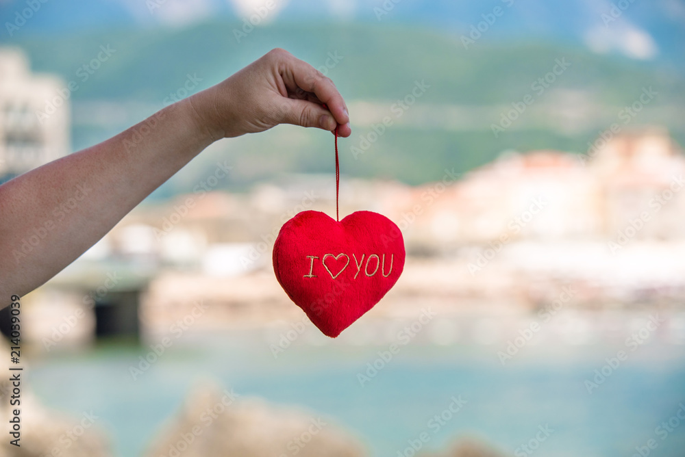 Fototapeta premium Girl holding a symbol of love over the sea 