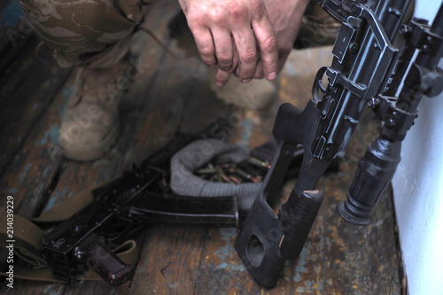 soldier hands and AK rifle on the floor. Sniper rifle