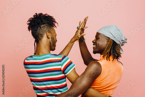 Fotografie, Tablou Having fun in a relationship - portrait of two men holding hands and dancing