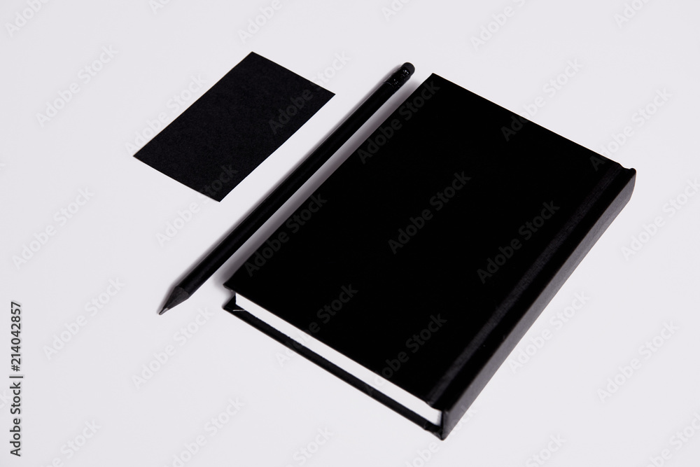 isometric view of black notebook with pencil and business card on white surface for mockup isometric view of black notebook with pencil and business card on white surface for mockup