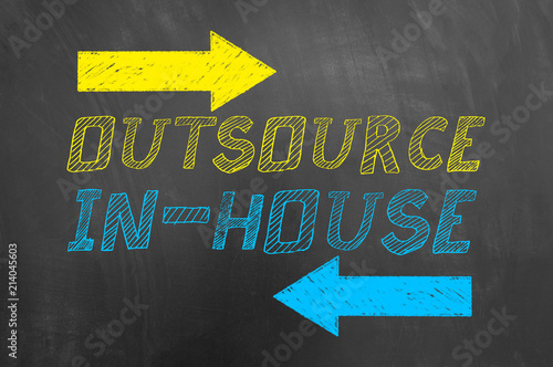 Outsource in house text and arrows on blackboard.