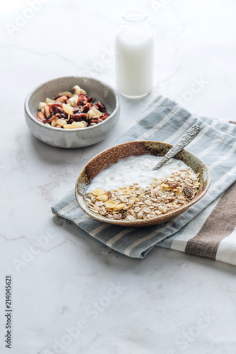Healthy breakfast. Fresh granola, muesli with yogurt, nuts and dried berries on marble background. 