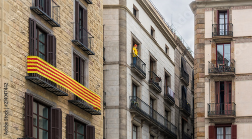 La Senyera ("flag" in Catalan) and mannequin on the balconies in Gothic Quarter of Barcelona. It is the official flag of Autonomous Community of Catalonia and symbol of pride for the Catalan people.