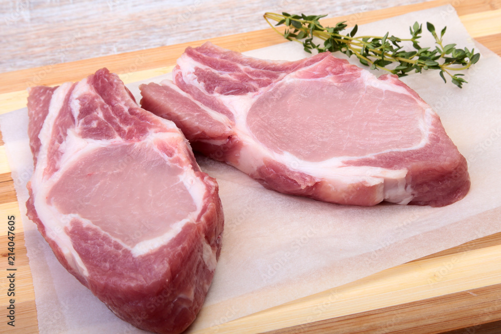 Raw pork chops, spices and rosemary on cutting board. Ready for cooking.