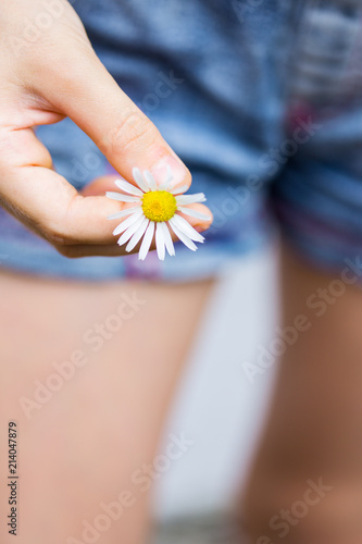 girl holds a daisy in her hand