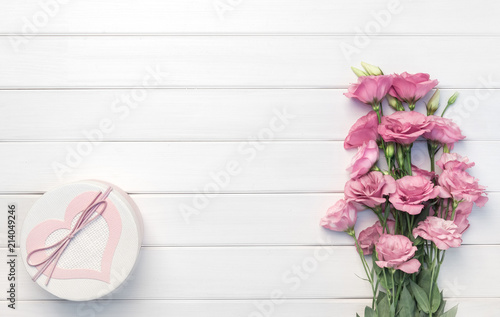 Beautiful pink eustoma flowers and handmade gift box on white wooden background. Copy space  top view 