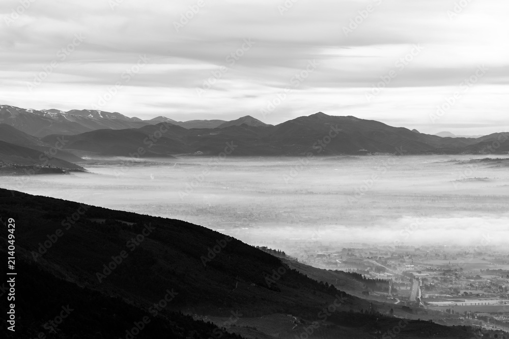 Beautiful aerial view of Umbria valley in a winter morning, with fog covering trees, houses and streets Beautiful aerial view of Umbria valley in a winter morning, with fog covering trees, houses and streets
