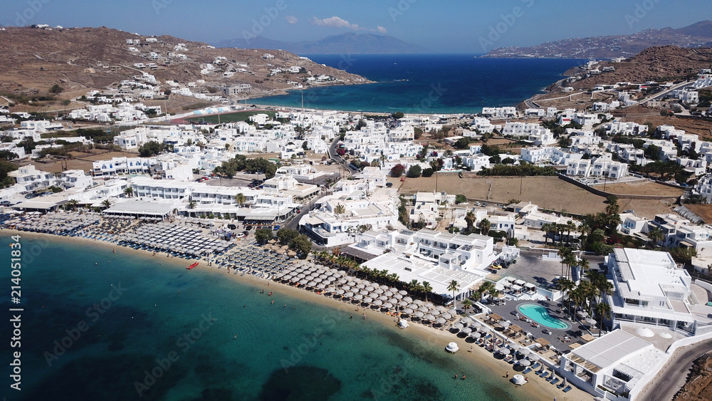 Aerial drone bird's eye view photo of famous organized with sun beds crystal clear water beach of Ornos in island of Mykonos, Cyclades, Greece