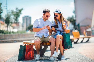 Happy couple paying on line with credit card and digital tablet on the street