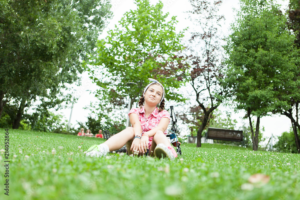 Happy teenager girl sitting on the grass in the park next to her bicycle Happy teenager girl sitting on the grass in the park next to her bicycle