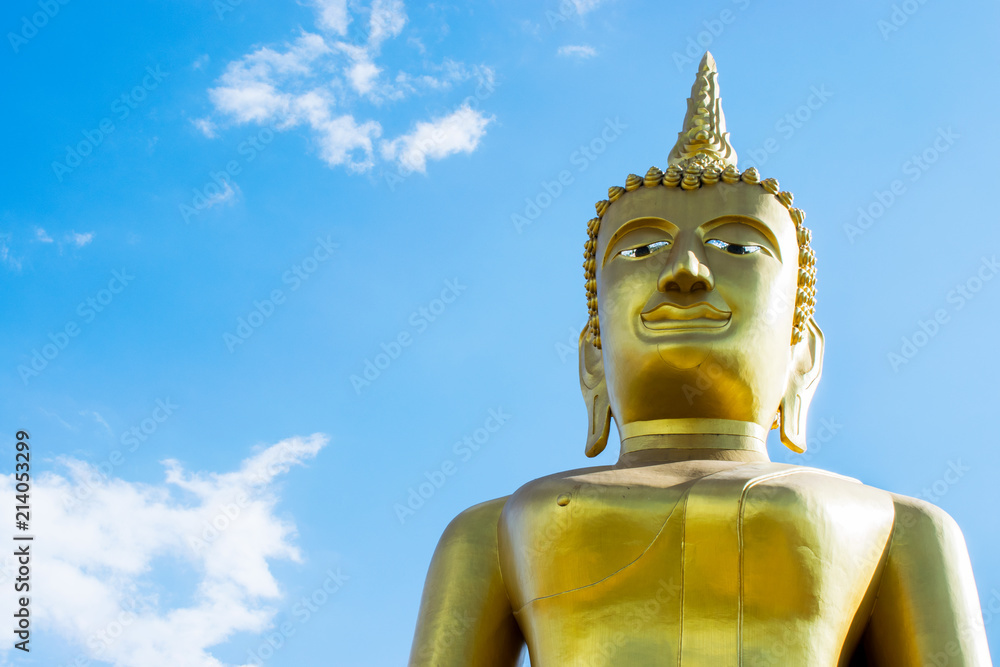 Big golden Buddha statue with blue sky background.