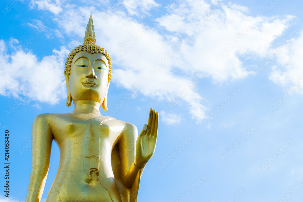 Big golden Buddha statue with blue sky background.