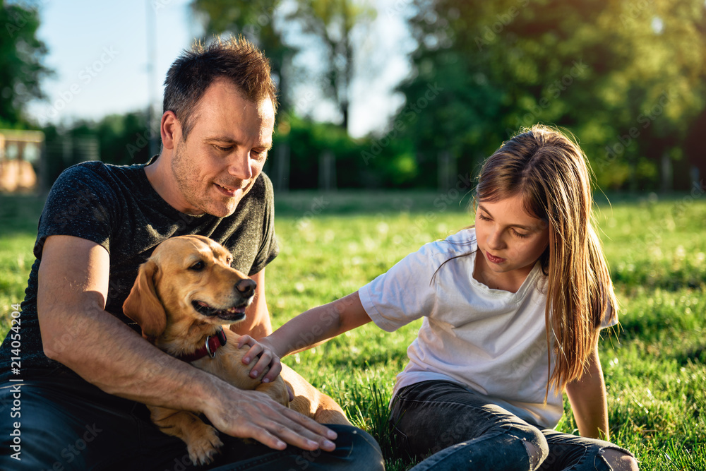 Father and daughter relaxing at park with dog