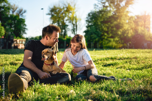 Bilde på lerret Father and daughter relaxing at park with dog
