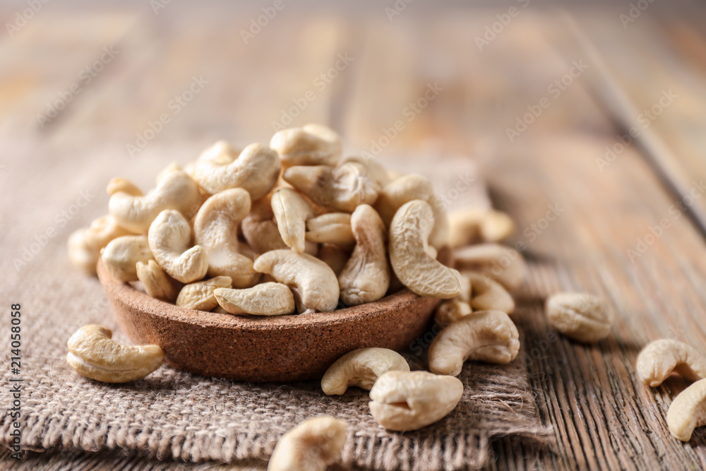 Plate with tasty cashew nuts on wooden table Plate with tasty cashew nuts on wooden table