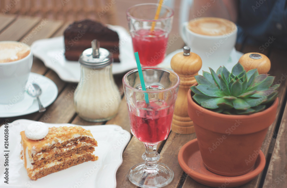 Wooden table on the summer terrace with cake, berry juice, succulent in a clay pot