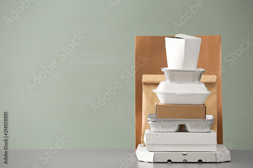 Different packages on table against color background. Food delivery service photo