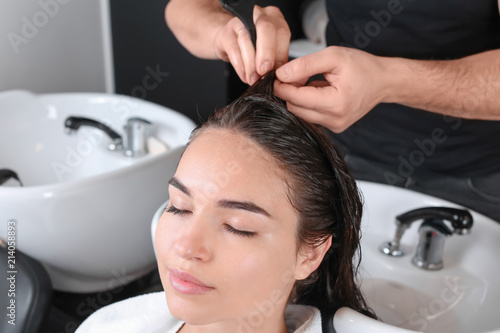 Professional hairdresser dyeing hair of young woman in beauty salon