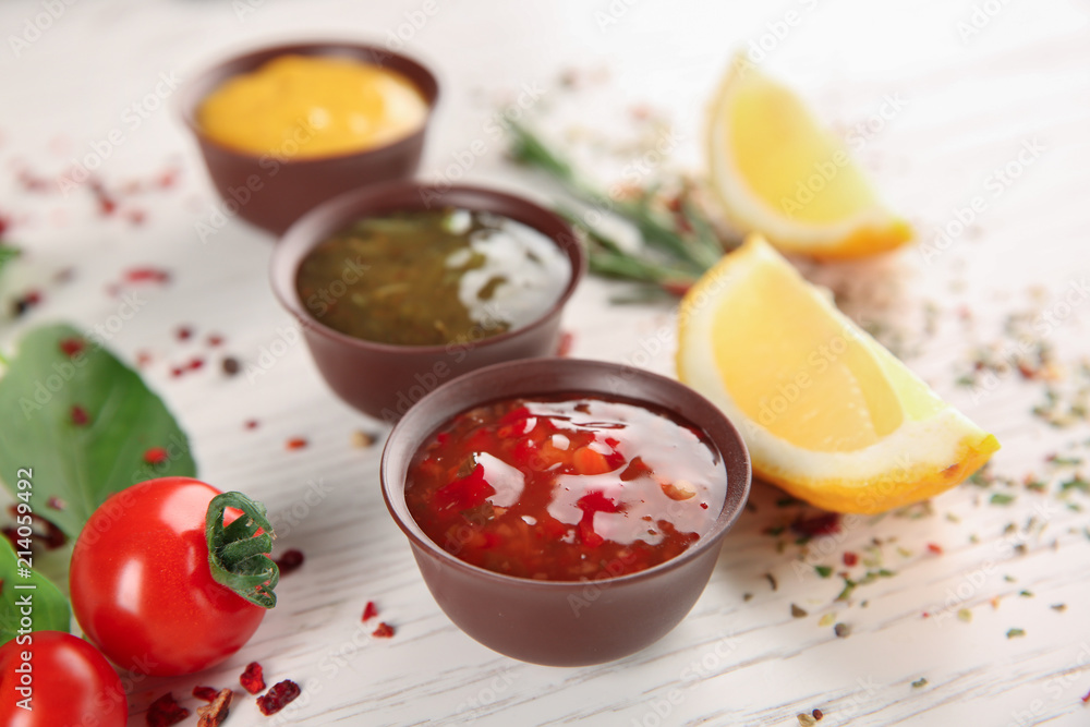 Bowls with different sauces and ingredients on light background Bowls with different sauces and ingredients on light background