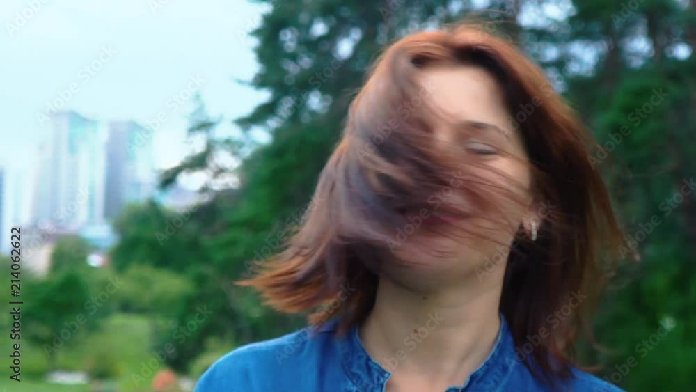 Portrait of a red-haired girl on a background of a green park shakes her hair. Face close-up. Young girl fooling around. Positive emotions Portrait of a red-haired girl on a background of a green park shakes her hair. Face close-up. Young girl fooling around. Positive emotions