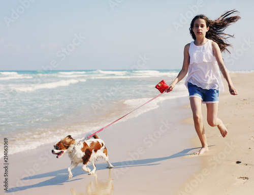 Portrait of  12 years old girl walking with her dog on the beach in summer day photo