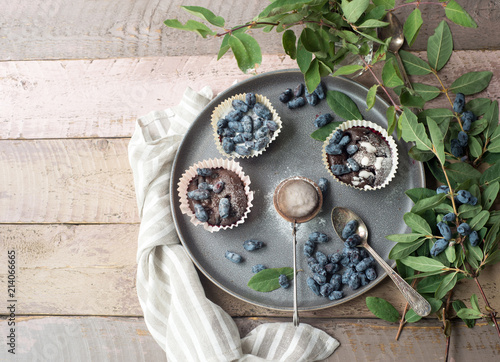 Honeysuckle berry and cup cakes with green leaves on a wooden table