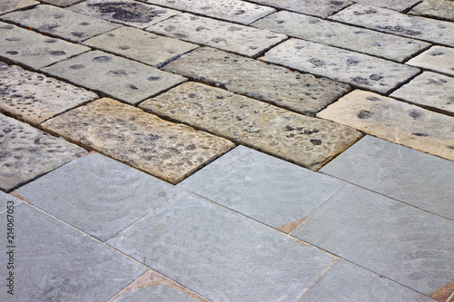 Restoratione of an old stone paving with new carved paving made with grey stone blocks in an italian pedestrian zone