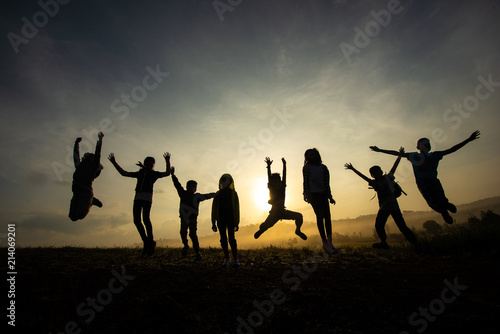 Silhouette of children jumping, happy and fun in the morning grassland, sunrise in nature.