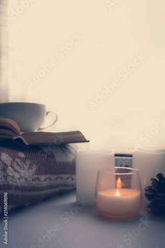 Details of still life in the home interior. Sweater, cup, wool, cozy, book, candle. Moody. Cosy autumn winter concept. Copy space