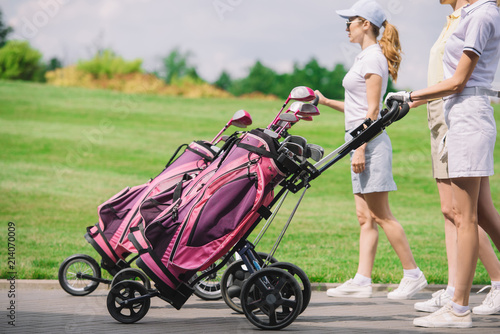 Partial view of female golfers with golf equipment walking at golf course