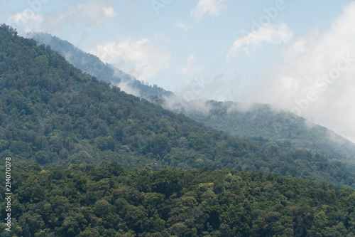 Tops of the mountains covered with forest in clouds and fog. Slopes of the mountains are covered with rainforest Bali, Indonesia. Mountain landscape, sky and clouds. Travel concept