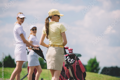 Canvastavla Selective focus of female golfers with golf equipment walking at golf course