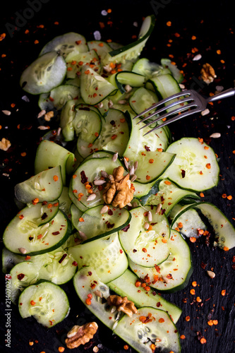 Lecker angerichteter Gurkensalat mit Gewürzen auf schwarzer Schieferplatte photo