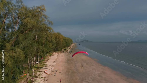 Paramotor flies away along the sandy beach in slow motion. The coast of Thailand. Trang province. Sikao. Paraglide. Para motor photo